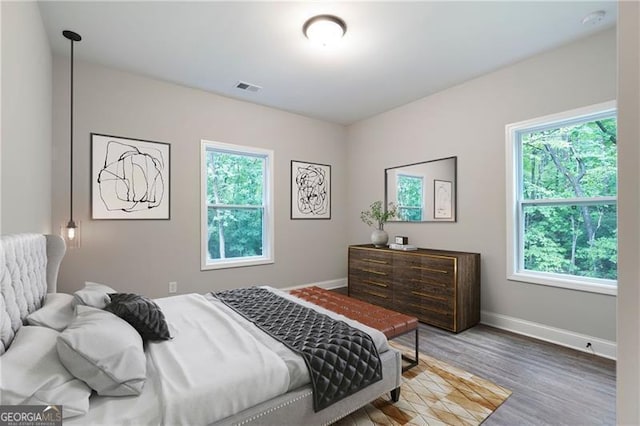 bedroom with visible vents, multiple windows, baseboards, and wood finished floors