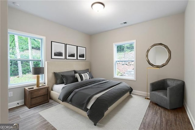 bedroom with visible vents, baseboards, and light wood finished floors