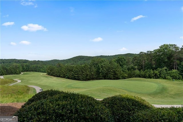 view of home's community featuring view of golf course and a wooded view