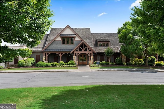 view of front of house featuring stone siding, french doors, and a front lawn