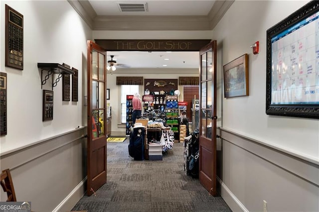 hallway featuring visible vents, baseboards, ornamental molding, and dark carpet