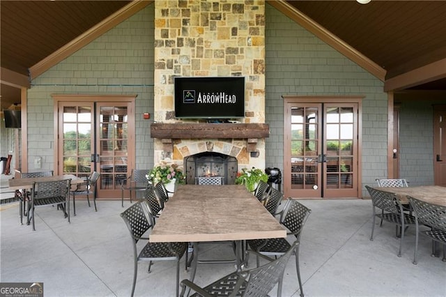 view of patio / terrace featuring outdoor dining space, french doors, and an outdoor stone fireplace