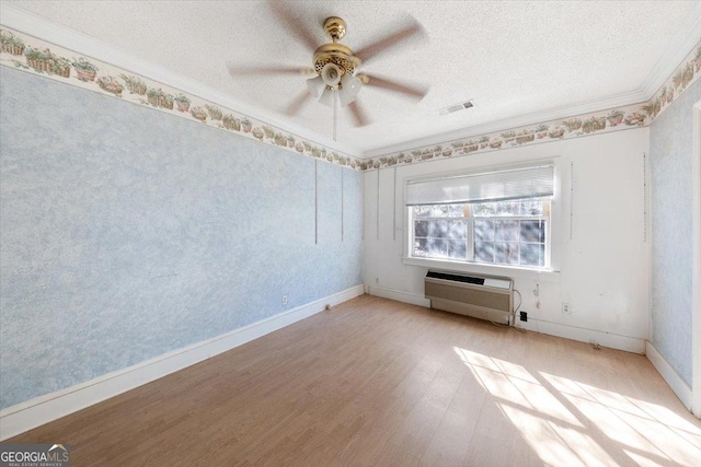 spare room with ceiling fan, light hardwood / wood-style flooring, an AC wall unit, crown molding, and a textured ceiling