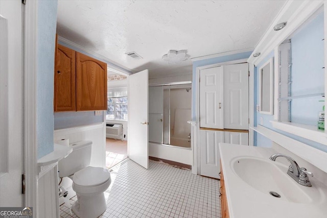 full bathroom with tile patterned flooring, an AC wall unit, bath / shower combo with glass door, toilet, and vanity