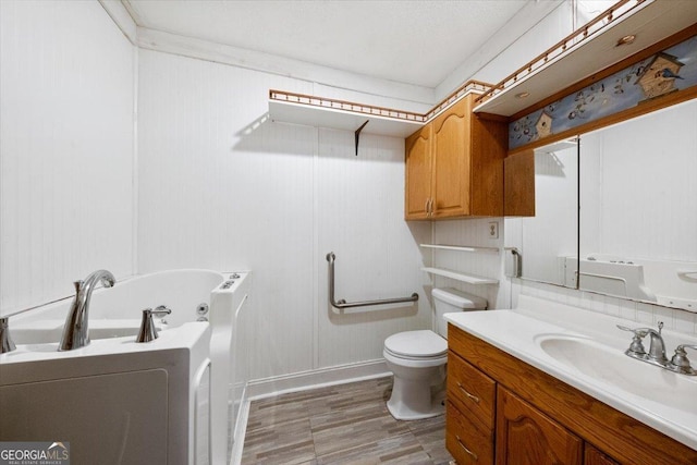 bathroom featuring vanity, a bathing tub, crown molding, toilet, and wood-type flooring