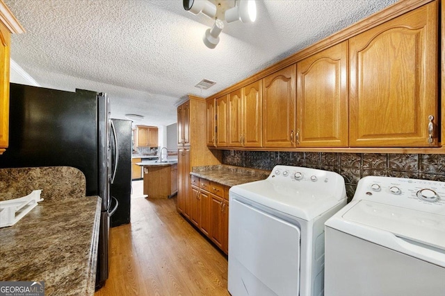 laundry area featuring washer and clothes dryer, light hardwood / wood-style floors, and a textured ceiling