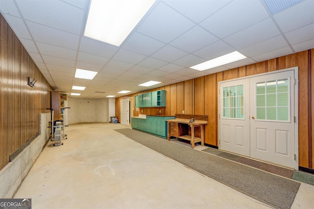 basement with a paneled ceiling and wooden walls