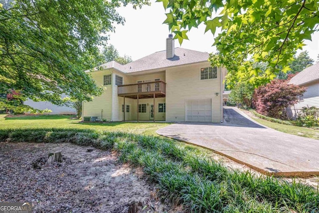 rear view of property with a wooden deck, a yard, and a garage