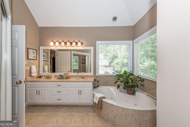 bathroom featuring vanity, a relaxing tiled tub, and vaulted ceiling