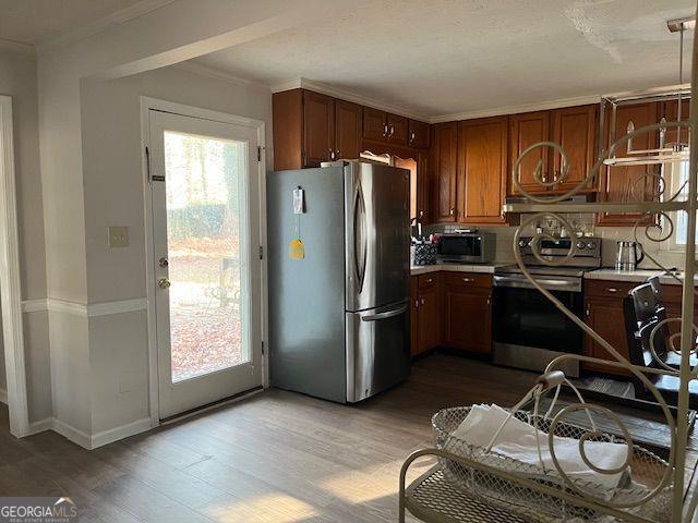 kitchen with ornamental molding, light hardwood / wood-style floors, and appliances with stainless steel finishes