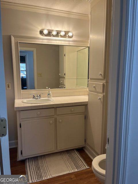 bathroom with vanity, hardwood / wood-style flooring, toilet, and ornamental molding