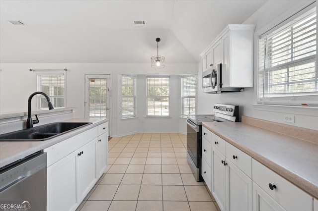 kitchen featuring stainless steel appliances, sink, white cabinets, vaulted ceiling, and hanging light fixtures