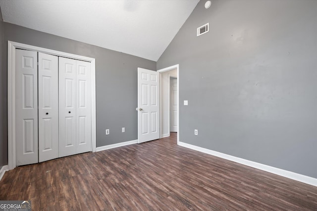 unfurnished bedroom with lofted ceiling, dark hardwood / wood-style flooring, and a closet