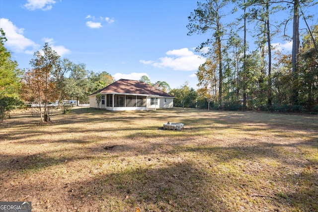 view of yard with an outdoor fire pit and a sunroom