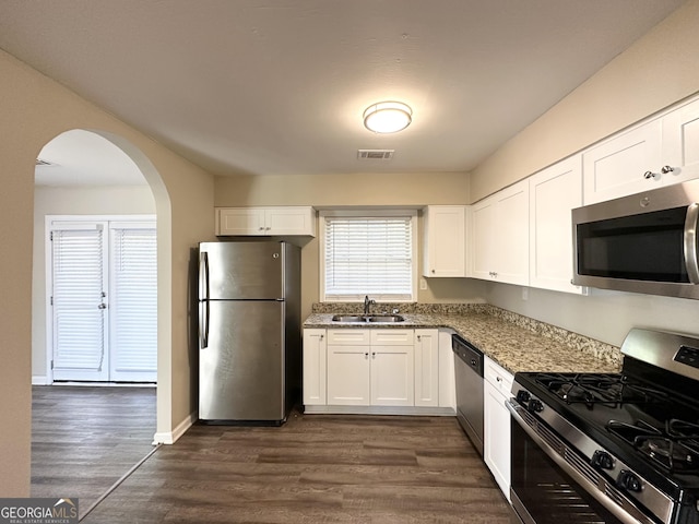 kitchen with white cabinets, stainless steel appliances, dark stone counters, and sink