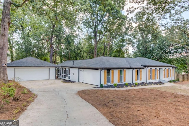 ranch-style house with an outbuilding, driveway, an attached garage, and stucco siding