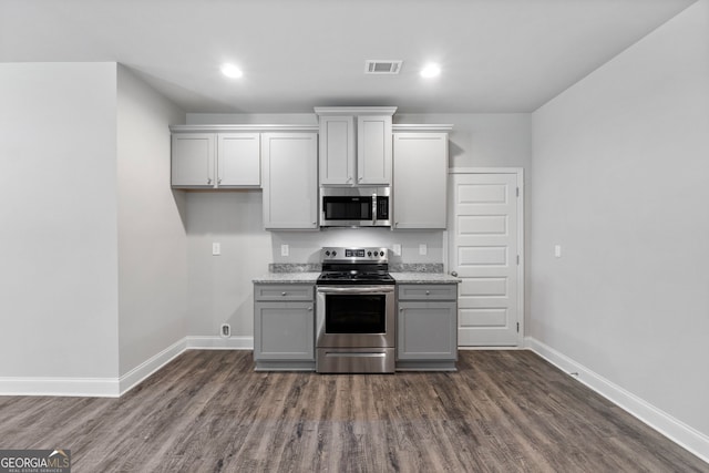 kitchen featuring light stone countertops, appliances with stainless steel finishes, gray cabinetry, and dark hardwood / wood-style flooring