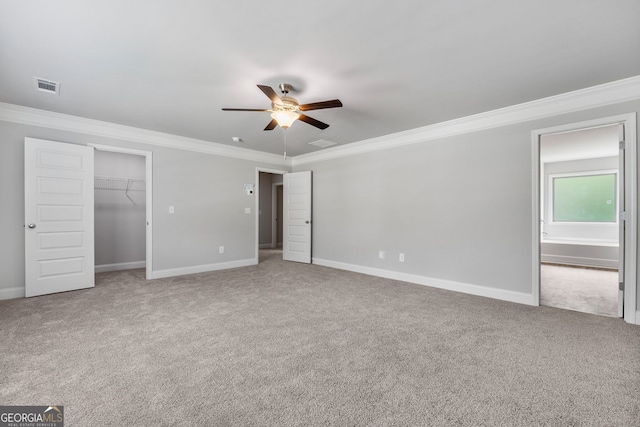 unfurnished bedroom featuring ornamental molding, carpet, a spacious closet, ceiling fan, and a closet