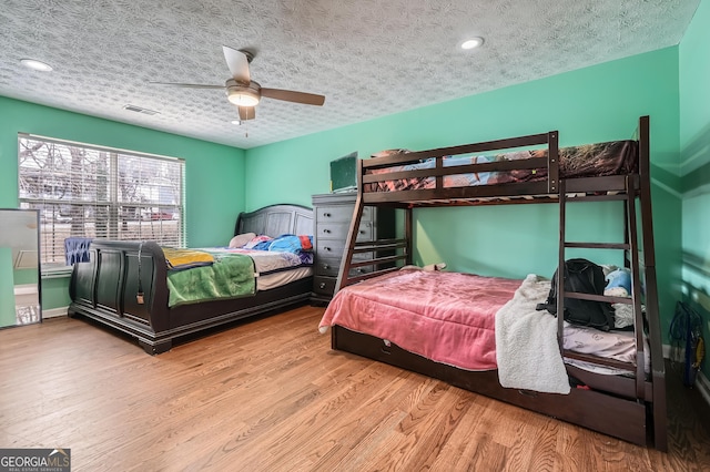 bedroom featuring ceiling fan, a textured ceiling, and light wood-type flooring