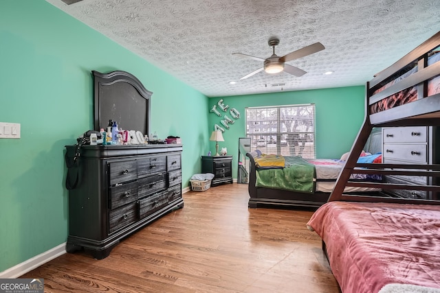 bedroom with wood-type flooring, a textured ceiling, and ceiling fan