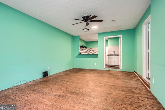 unfurnished bedroom featuring ceiling fan, sink, ensuite bathroom, a textured ceiling, and hardwood / wood-style flooring