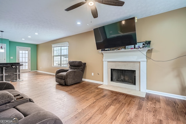 living room featuring a textured ceiling, hardwood / wood-style flooring, ceiling fan, and a premium fireplace