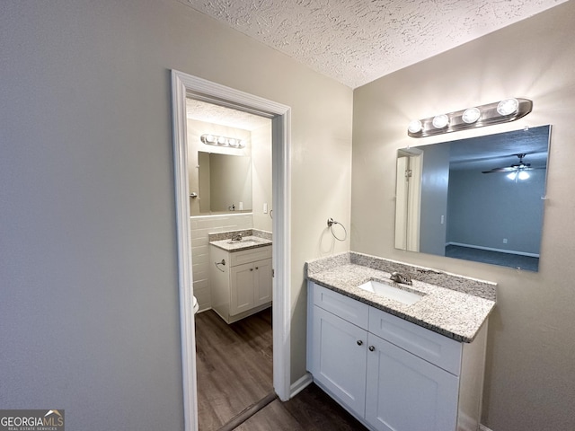 bathroom featuring vanity, ceiling fan, wood-type flooring, and a textured ceiling