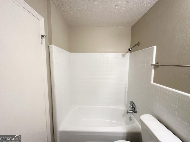 bathroom featuring shower / bathing tub combination, a textured ceiling, toilet, and tile walls