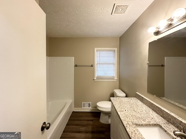 bathroom with vanity, a washtub, toilet, a textured ceiling, and wood-type flooring