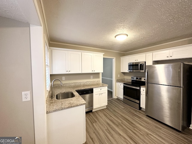 kitchen featuring light stone countertops, stainless steel appliances, sink, light hardwood / wood-style floors, and white cabinetry