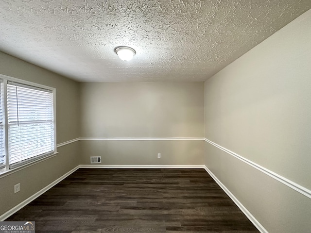 empty room featuring a textured ceiling and dark hardwood / wood-style floors