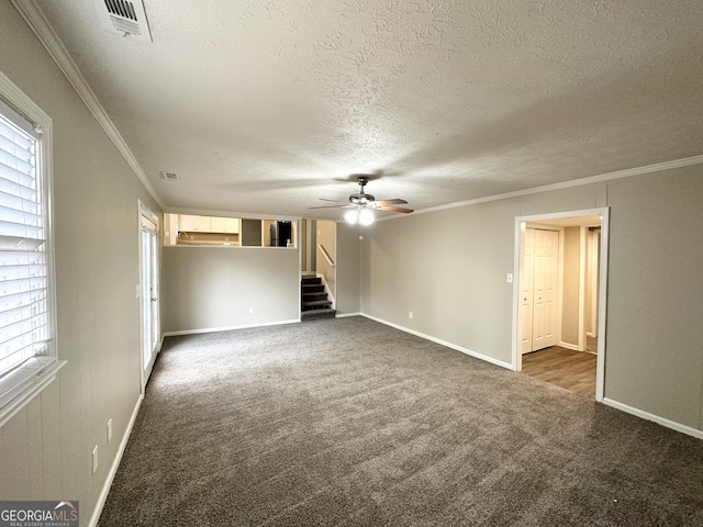 spare room featuring dark colored carpet, a textured ceiling, ceiling fan, and crown molding