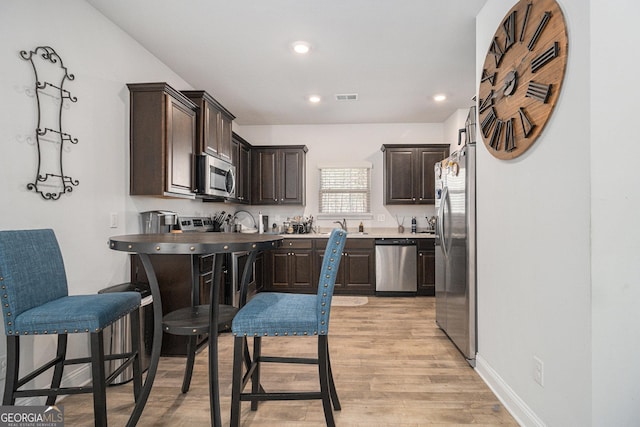 kitchen featuring dark brown cabinetry, sink, stainless steel appliances, and light hardwood / wood-style floors