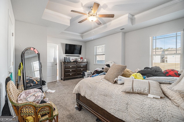 bedroom featuring ornamental molding, a tray ceiling, ceiling fan, and light colored carpet