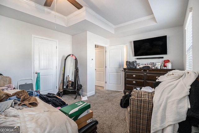 carpeted bedroom with a tray ceiling, ceiling fan, and crown molding