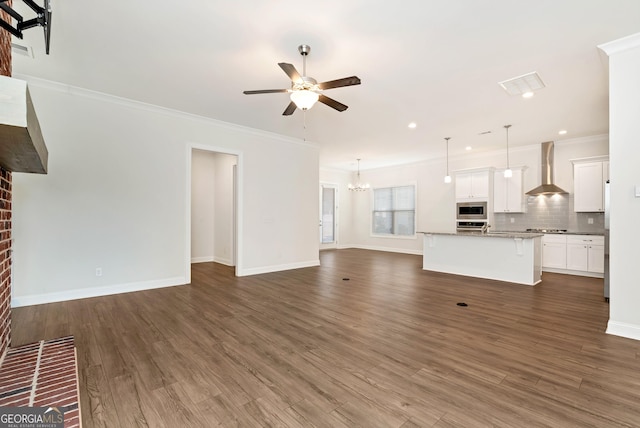unfurnished living room featuring ceiling fan with notable chandelier, dark hardwood / wood-style flooring, a brick fireplace, and crown molding