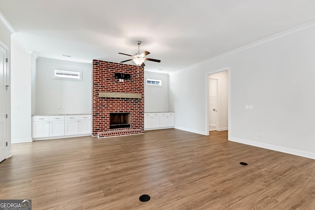 unfurnished living room featuring a fireplace, crown molding, and a healthy amount of sunlight