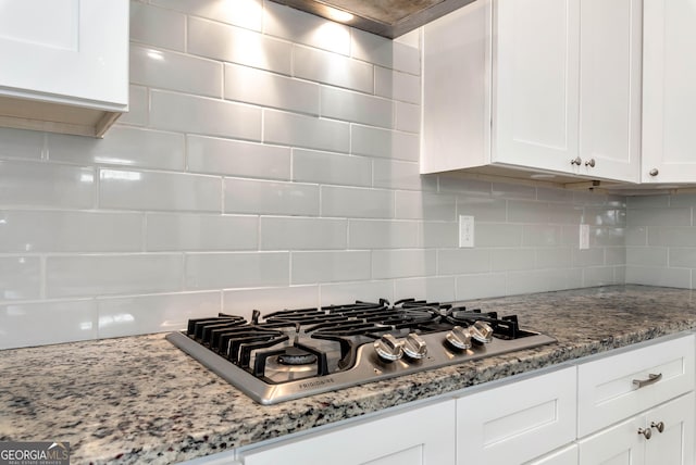 kitchen with tasteful backsplash, light stone counters, white cabinetry, and stainless steel gas stovetop