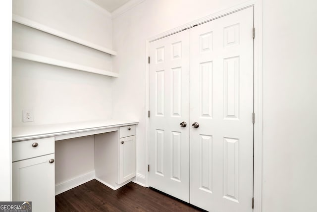 unfurnished office with built in desk, dark hardwood / wood-style floors, and crown molding