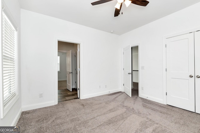 unfurnished bedroom featuring multiple windows, light colored carpet, and ceiling fan