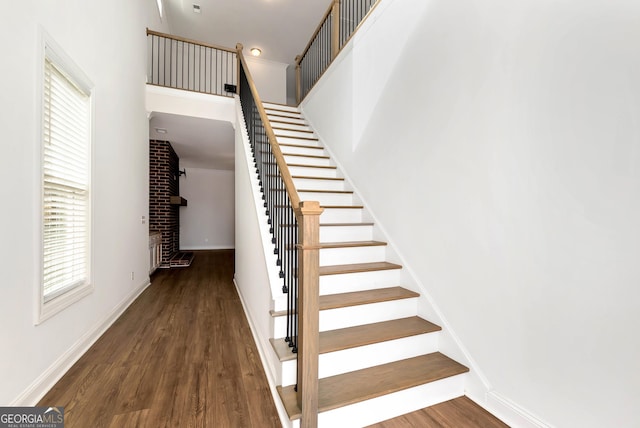 staircase with a fireplace and hardwood / wood-style floors