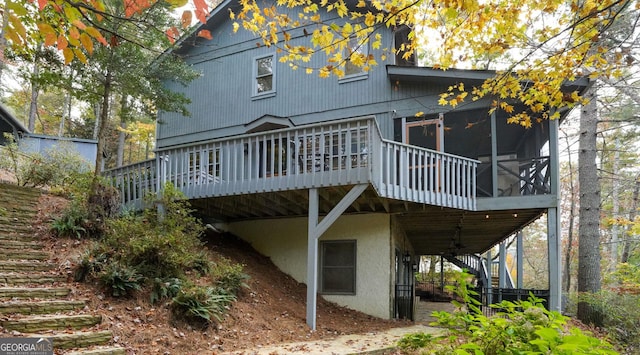 back of property with a sunroom, ceiling fan, and a deck