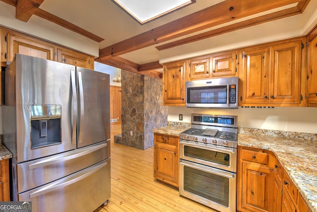 kitchen with beam ceiling, light stone counters, light hardwood / wood-style floors, and appliances with stainless steel finishes