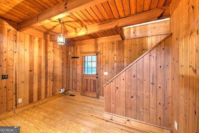 foyer entrance featuring beamed ceiling, light wood-type flooring, and wooden walls