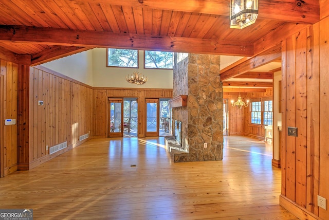 foyer featuring beamed ceiling, wood walls, light hardwood / wood-style flooring, and a chandelier