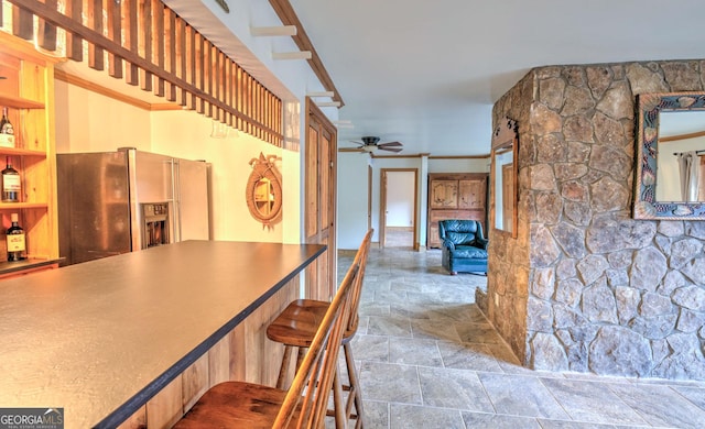 kitchen featuring ceiling fan, stainless steel fridge, and a breakfast bar