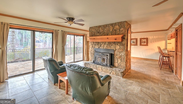 living room with ceiling fan, a wood stove, and ornamental molding