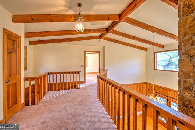 hall featuring vaulted ceiling with beams, carpet floors, wooden walls, and an inviting chandelier