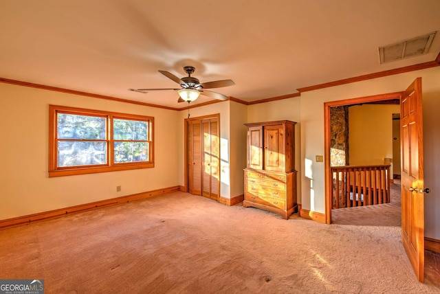 empty room featuring ceiling fan, light carpet, and ornamental molding