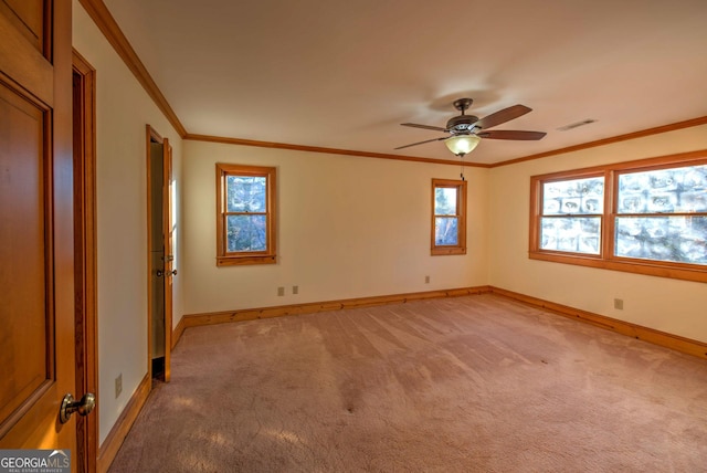 carpeted spare room with a wealth of natural light, ornamental molding, and ceiling fan